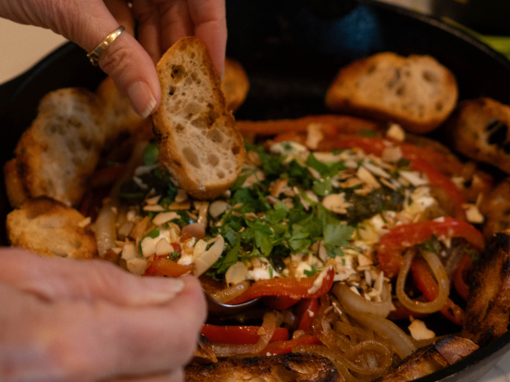 hand dipping crostini into goat cheese pesto