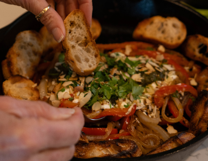 hand dipping crostini into goat cheese pesto